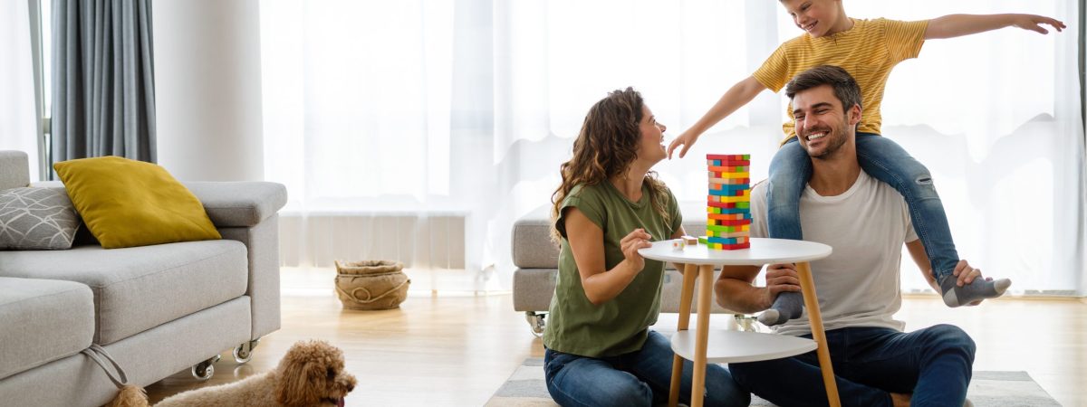 Happy young family having fun time, playing together at home with dog